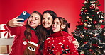 Happy mom, children or christmas tree with selfie in studio for photography on a red background. People, mother or kids with smile, goofy or silly faces for festive holiday, picture or capture moment