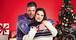 Christmas, hug and face with couple in studio together for bonding and gift or present. Portrait, celebration or smile with man and woman embracing on red background for festive tradition or holidays