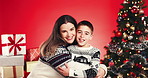 Christmas, hug and face of mother and son in studio for holiday season, smile and bonding. Festive celebration, love and December break with woman and child on red background for family and support