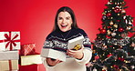 Happy woman, face and christmas surprise with gift box in studio for giving on a red background. Portrait, female person or model with smile for present, festive celebration or december holiday