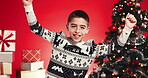 Christmas, excited and boy in studio for dance, tradition and happy on red background. Xmas, holiday season and child with presents, energy and celebration for festive event and vacation party