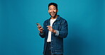 Face, phone and surprise with man in studio for lottery winner, good news and notification. Announcement, online prize and chat with excited person and mobile on blue background space for giveaway