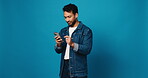 Scroll, phone and smile with man in studio for social media, text message and communication. Connection, browsing online and chat with person and mobile on blue background space for network and app