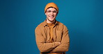 Face, smile and man with arms crossed, mockup and confidence on blue background in studio. Portrait, happy Gen z person and aesthetic with trendy, casual outfit and comfortable clothes on space