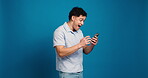 Studio, excited and man with smartphone, browsing and surprised by news on website and mockup space. Blue background, shocked and person with mobile, happy and notification on app or communication