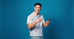 Pointing, phone and face with man in studio for giveaway, promotion and communication. Announcement, online notification and chat with person and mobile on blue background space for network and app