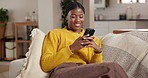 Black woman, living room and smile with phone, typing and social media for funny meme on home sofa. African person, couch and mobile app with laugh, online dating or message in apartment lounge