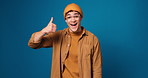 Happy man, face and reaction with thumbs up in studio for surprise on a blue background. Portrait, male person or model with smile, like emoji or yes sign for positive feedback or expression on space