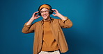Man, headphones and smile with dancing in studio, streaming and music subscription on blue background. Person, audio tech and listen with song, radio or happy for album with eyes closed for sound