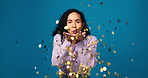 Happy woman, face and blowing with confetti for golden opportunity in studio on a blue background. Portrait, female person or model with glitter or sparkle for new year celebration on mockup space
