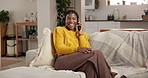 Black woman, phone call and laugh on sofa in home with funny chat, memory or story in living room. African girl, smartphone and relax on couch, happy and listen with conversation for gossip at house