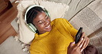 Black woman, headphones and singing with phone on sofa, above and scroll on social media at home. African girl, smartphone and audio tech with mobile app, chat and streaming subscription at apartment