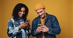 Gen z couple, phone and happy in studio with texting, fashion and laugh at meme on yellow background. Man, woman and smile with smartphone, talk and mobile app for funny video on social network