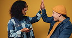 Couple, smartphone and happy with high five in studio for celebration, goals or online prize on yellow background. Gen z man, woman and excited with phone, success and app for competition giveaway