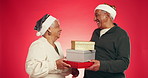 Present box, happy and senior couple with christmas surprise in studio for marriage tradition on holiday. Love, smile and elderly man with woman for xmas gifts with celebration by red background.