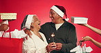 Sparkler, christmas gifts and senior couple in studio with tradition, celebration or festive season. Happy, fireworks and hands with presents by elderly man with woman for holiday by red background.