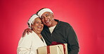 Christmas, gift and face of couple in studio for love, holiday season and festive celebration. Romance, xmas present and bonding with elderly man and woman on red background for tradition and smile