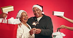 Sparkler, christmas presents and senior couple in studio with tradition, celebration or festive season. Hug, fireworks and hands with gifts by elderly man with woman for holiday by red background.