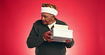 Christmas, gift and shake with old man in studio for announcement, holiday season and boxes. Festive celebration, Xmas present and December break with elderly person on red background space for guess