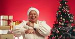 Christmas, dance and face of senior woman in studio with decoration for holiday or festive season. Happy, mockup space and portrait of mature person with energy for xmas celebration on red background