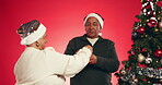 Old couple, Christmas and tree decoration in studio, festive love with bauble or ornament for holiday decor. Help, celebration and senior people with glitter ball for December break on red background