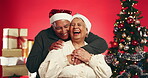 Christmas, hug and face of old couple in studio for love, holiday season and festive celebration. Romance, xmas and laughing with elderly man and woman on red background for tradition and smile