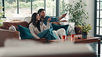 Couple, remote and watching tv with pointing on sofa for movie choice, bonding and search show. Hug, happy people and conversation in house for film subscription, weekend break and streaming service
