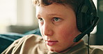 Face, gaming and headset with boy in living room of home for challenge, esports or hobby. Concentration, entertainment and playing with video gamer child on sofa in apartment for online competition