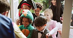 Children, halloween and happy at front door for candy, trick or treat with man at home for holiday. Neighborhood kids, excited and dress up with sweets container, festival and collection at house