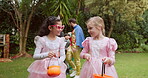 Halloween, smile and walking with girls outdoor in garden for celebration, holiday or tradition. Bucket, costume and trick or treat with children friends talking in backyard together for bonding