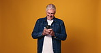 Funny, cellphone and senior man in studio, online reading and happiness on yellow background. Space, texting and elderly person with smartphone, connection and humor with smile and message to contact