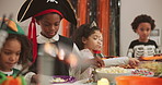 Boy, snacks and children at halloween party, popcorn and sweets with celebration at home. Kids, food and candy with pirate costume with trick or treat, holiday and tradition for friends at house