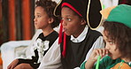 Children, costume and eating with halloween candy for festive holiday or party on sofa in home. People, group or kids with cosplay for fairy tale day, tradition and trick or treat together in house