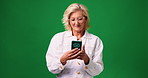 Phone, smile and mature woman in studio with communication, networking or contact on mobile app. Technology, happy and person with cellphone for connectivity, texting or chatting by green background.