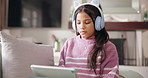 Tablet, headphones and kid in home for online education, virtual lesson and streaming sound. Elearning, technology and girl child with audio in living room for internet, app and course on sofa