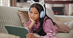 Child, resting and tablet with headphones at house for streaming, watch movie and listen to kpop. Girl, relax and digital for reading audiobook, cartoon video and anime film for weekend entertainment