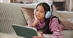 Child, relax and tablet with headphones at house for streaming, watch movie and listen to kpop. Girl, resting and digital for reading audiobook, cartoon video and anime film for weekend entertainment