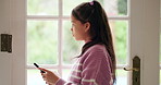Thinking, sad and kid with phone in home for cyberbullying or social media addiction. Reflection, girl and unhappy child with mobile for text of cyber stalker, reading message and anxiety by door