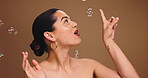 Beauty, bubbles and cosmetics with excited woman on studio space for energy, fun or satisfaction. Funny, makeup and popping with happy model laughing on wall background for hydration or hygiene