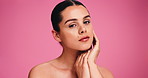 Touch, skincare and face of woman in studio for beauty, self care and glow aesthetic. Collagen, dermatology and shine with female person and hands on pink background for mockup space and clear skin