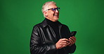 Funny, smartphone and senior man in studio, typing and happiness on green background. Space, laughing and elderly person with cellphone, texting and humor with joke, smile and online comedy video