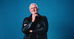 Crossed arms, fashion and face of mature man in studio with thinking for casual, trendy or cool outfit. Happy, ideas and portrait of male person from Australia with edgy clothes by blue background.