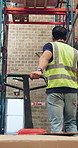 Construction, factory and back of man with trolley for supply chain, logistics and distribution. Warehouse, manufacturing and person walking with pallet jack for delivery, shipping and packaging