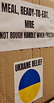 Ukraine, shipping and charity box in warehouse for famine relief, crisis response and food package. Outreach, MRE and caution label on cardboard parcel for social responsibility and NGO distribution