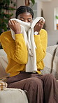 Smelling, clothes and black woman in home for housekeeping, maintenance or spring cleaning. Happy, fabric and African female person with scent on material of laundry in living room at apartment.