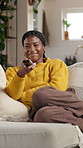 Black woman, watching tv and happy on sofa in home, remote control or streaming comedy in lounge. African girl, smile and relax on couch with funny movie, film or subscription in living room at house