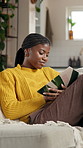 Black woman, reading book and relax on couch, home and learning with novel, story or study in lounge. African person, student and literature on sofa for research, project or education in living room