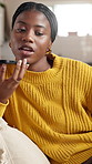 Black woman, speakerphone call and talk on sofa, relax or happy with chat in living room at home. African person, smartphone and smile for discussion, gossip or laugh at funny story on couch at house