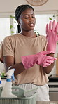 Black woman, cleaning and gloves with basket in kitchen for housekeeping service or hygiene in home. Female person, homeowner and getting ready with detergent supplies for disinfection in house