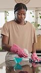 Black woman, cleaning or gloves with spray bottle in kitchen for housekeeping service or hygiene. Female person, homeowner or wiping surface with cloth or chemical detergent for disinfection in house